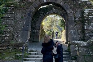 Photo of blind friends walking up some steps through an ancient Irish archway on monastery grounds